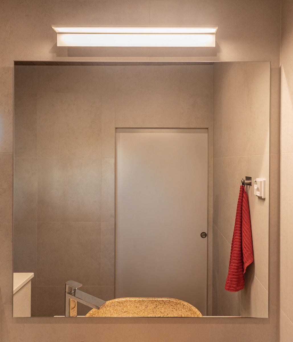In the shower area above the basin, a white BLADE600 wall lamp with aluminium rims provides uniform illumination. The light has a warm colour temperature of 3 000 Kelvin.